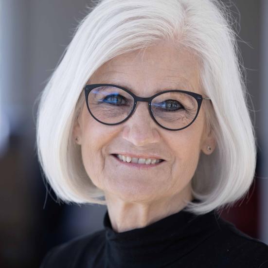 billede af smilende kvinde med gråt hår og briller