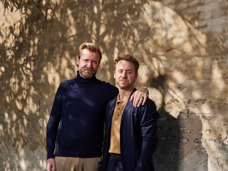 billede af to mænd der står foran en mur