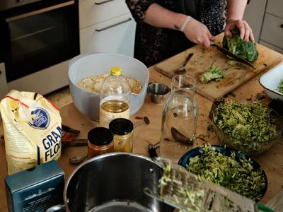 billede af køkkenbord med køkkenudstyr, råvarer og arbejdende persson