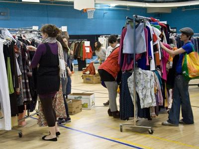 Billede af fyldte tøjstativer og mennesker der ser på tøjet