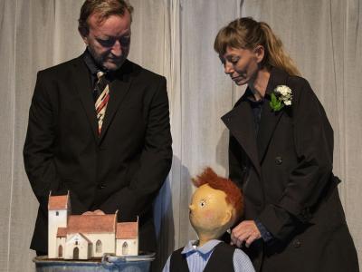 billede af en mand, en kvinde og en dukke der kigger på en model af en kirke