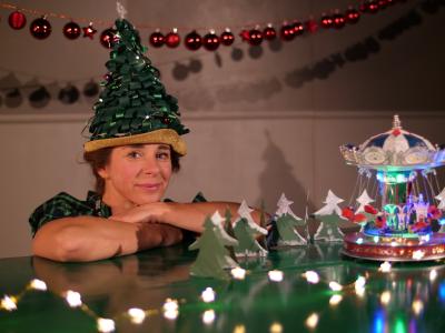 Billede af kvinde med der sidder ved bord med julepynt med en grøn hat udformet som et juletræ