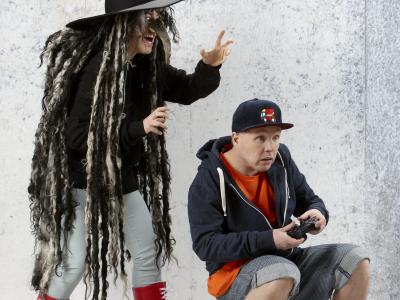 Billedet forestiller en dreng, der sidder og spiller Playstation og en heks spillet af to skuespillere.