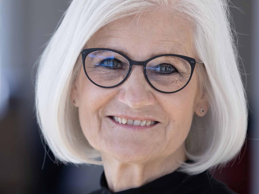 billede af smilende kvinde med gråt hår og briller