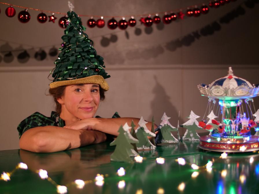 Billede af kvinde med der sidder ved bord med julepynt med en grøn hat udformet som et juletræ