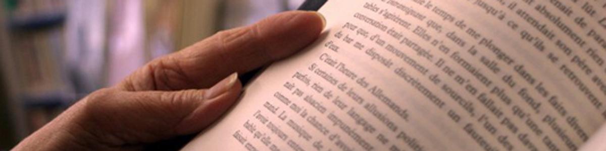 Nærbillede af tekst i bog og en hånd der holder bogen