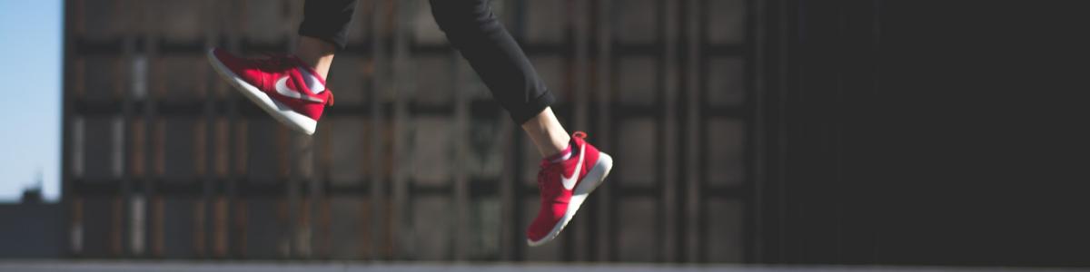 Billedet viser den nederste del af et ungt mennesket der hopper højt op en gade.