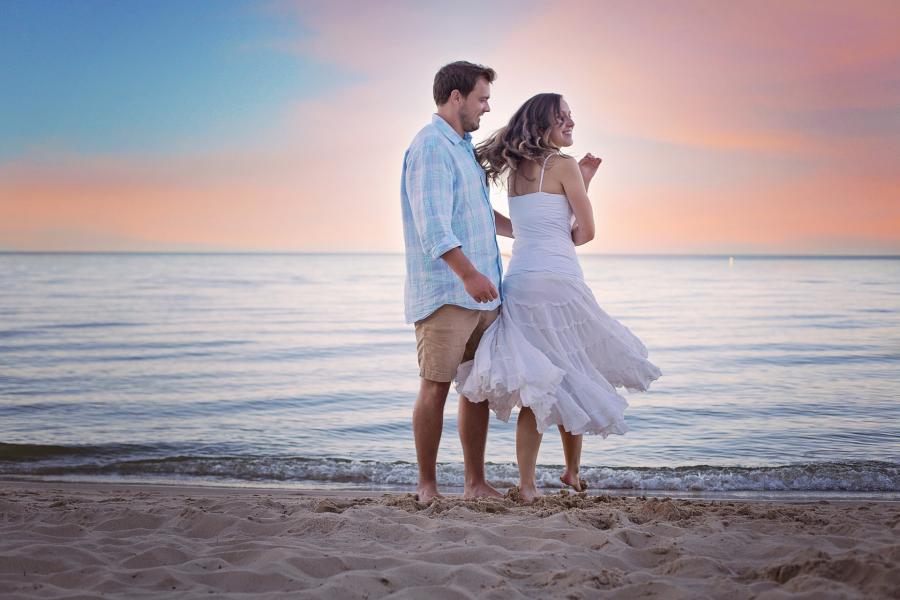 Billedet viser en mand og en kvinde der går tæt sammen på en strand.