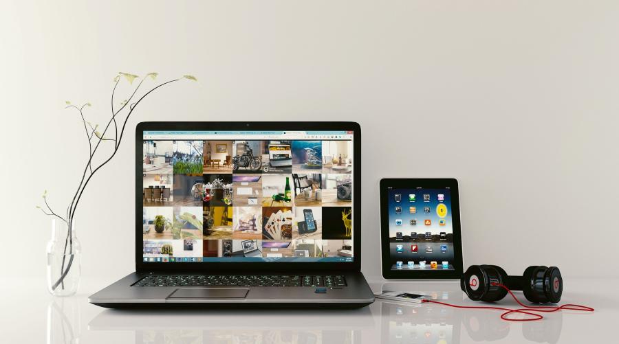 Billedet viser en bærbar computer, en iPad og en telefon med høretelefoner tilkoblet