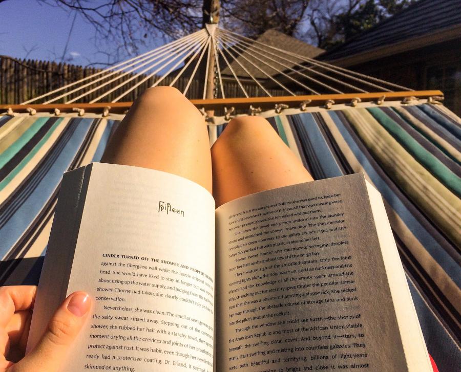 En bog hviler på benene af en person i en hængekøje