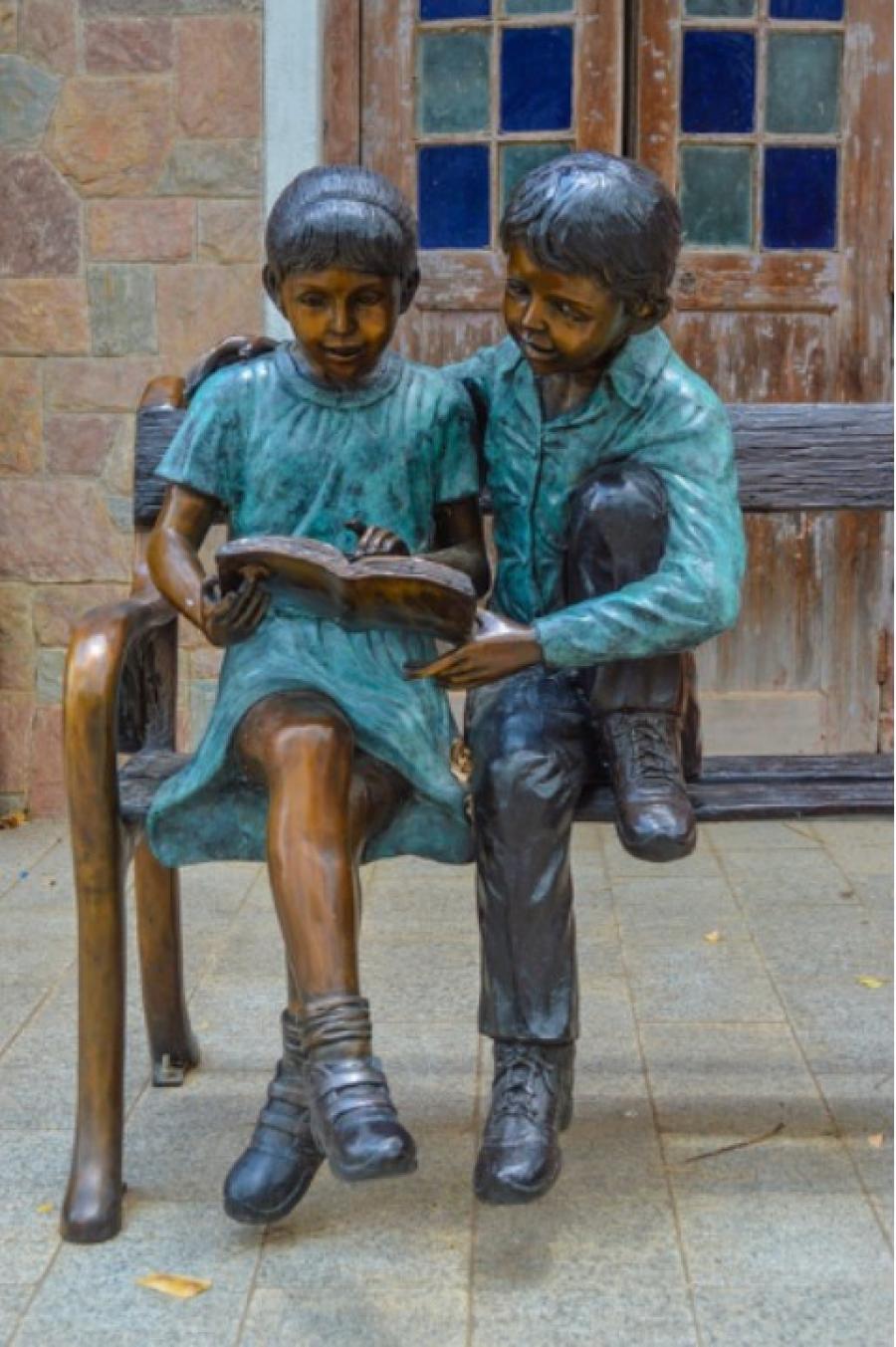 Statue af pige og dreng der læser en bog