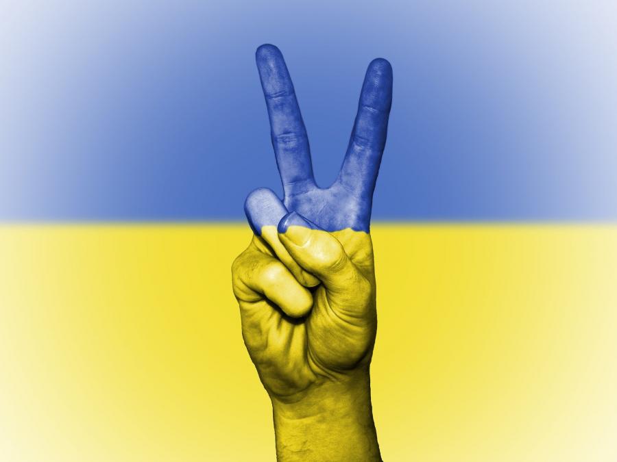 Billedet viser en hånd, der laver peacetegn foran det ukrainske flag.